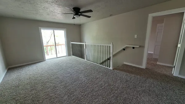 an empty room with a window and a fan