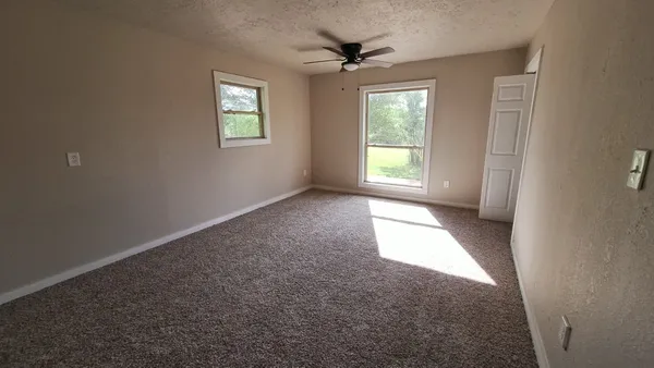 an empty room with a window and a fan
