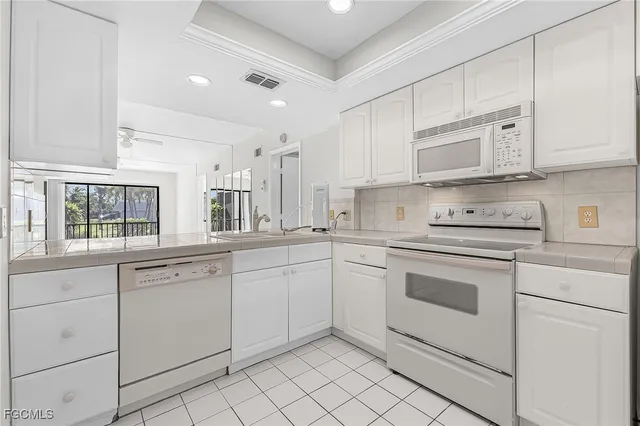 a kitchen with white cabinets and white appliances