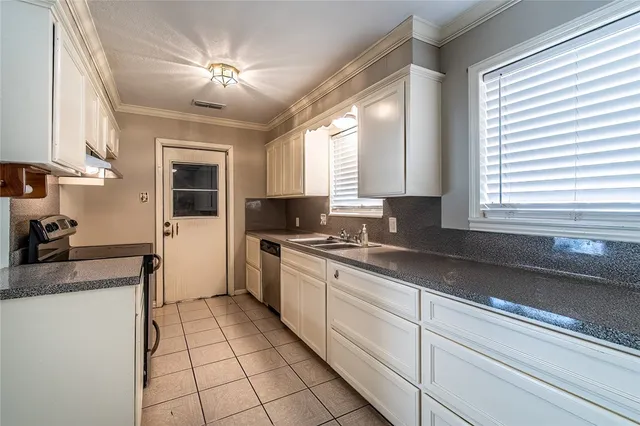 a kitchen with a sink appliances cabinets and a window