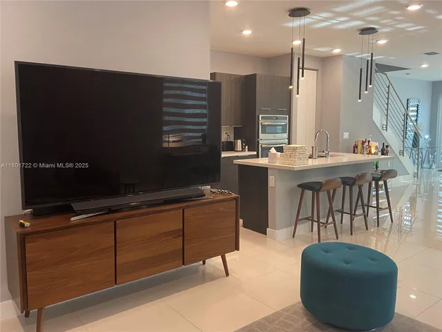 a living room with furniture a flat screen tv and kitchen view