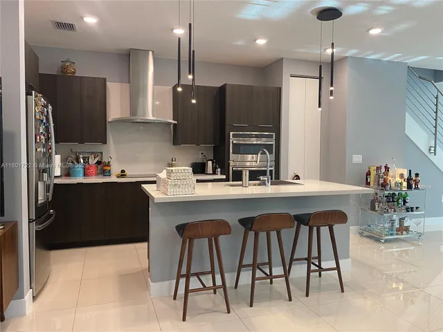 a kitchen with stainless steel appliances kitchen island granite countertop a sink and a refrigerator