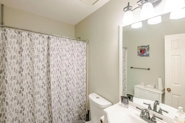 a bathroom with a sink a toilet and shower curtain