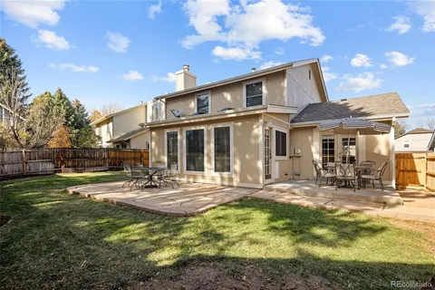 a patio with a table and chairs and plants