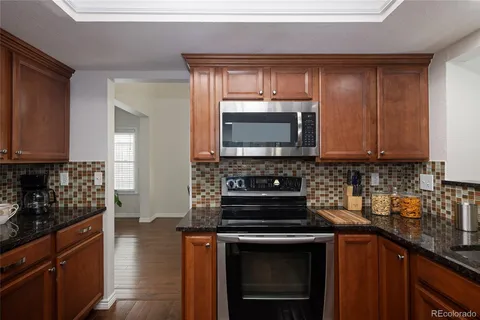 a kitchen with granite countertop a stove top oven microwave and cabinets