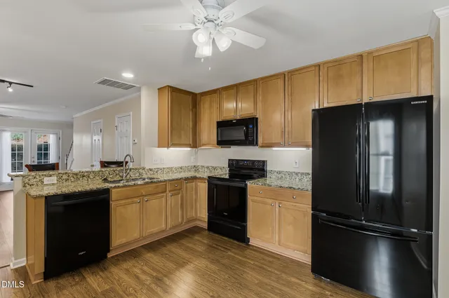 a kitchen with stainless steel appliances granite countertop a sink stove refrigerator and cabinets
