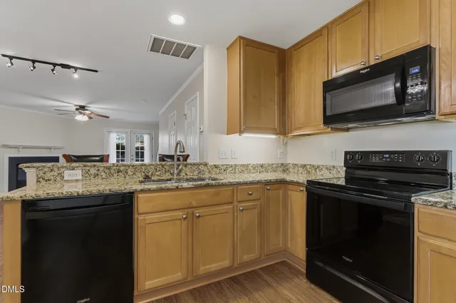 a kitchen with granite countertop a refrigerator stove top oven and sink