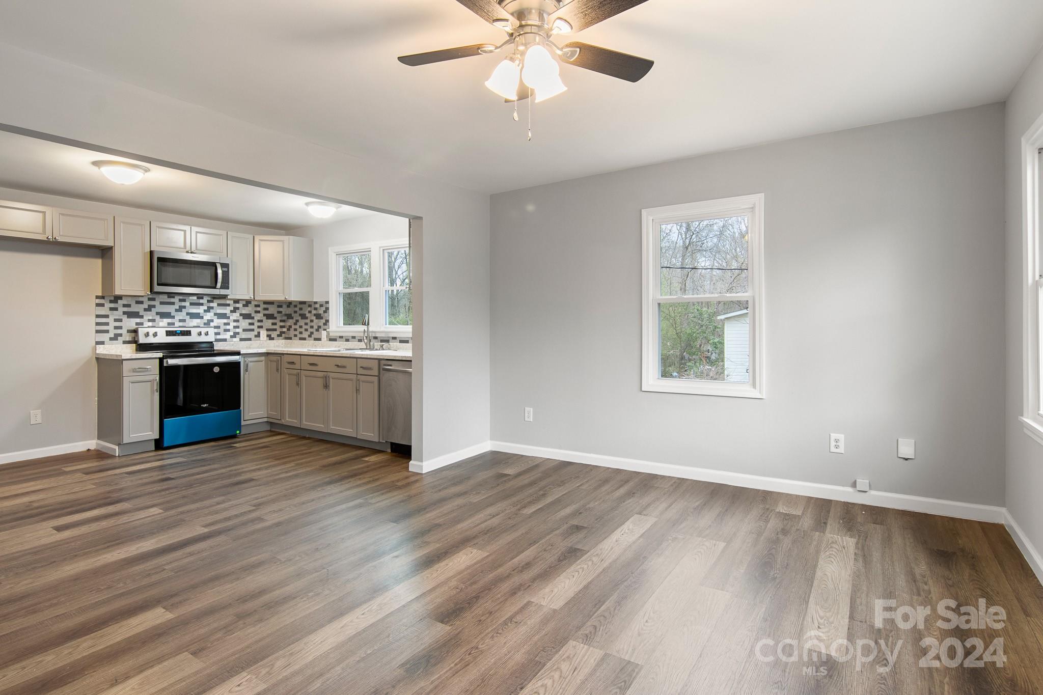 233 Charlotte Street York, SC 29745 - Photo 5 of 26 an empty room with wooden floor kitchen view and a fireplace