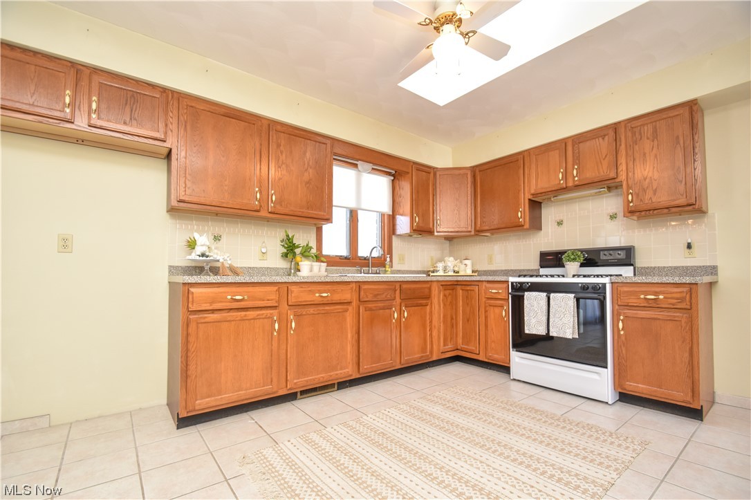 5050 Canfield Road Canfield, OH 44406 - Photo 5 of 47 Kitchen featuring light tile flooring, backsplash, and white range with gas cooktop