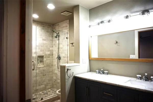 a bathroom with a double vanity sink mirror and shower