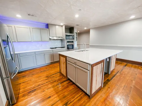 a kitchen with stainless steel appliances granite countertop a stove top oven a sink and a refrigerator