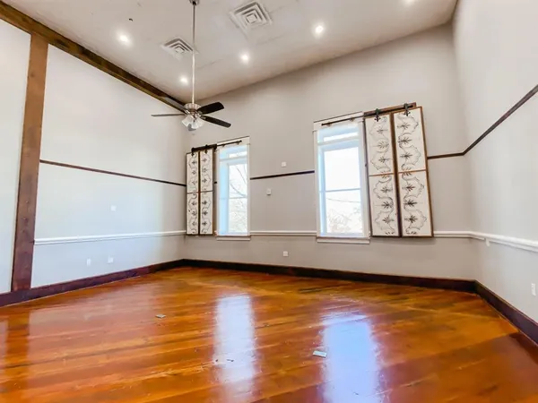a view of empty room with wooden floor and fan