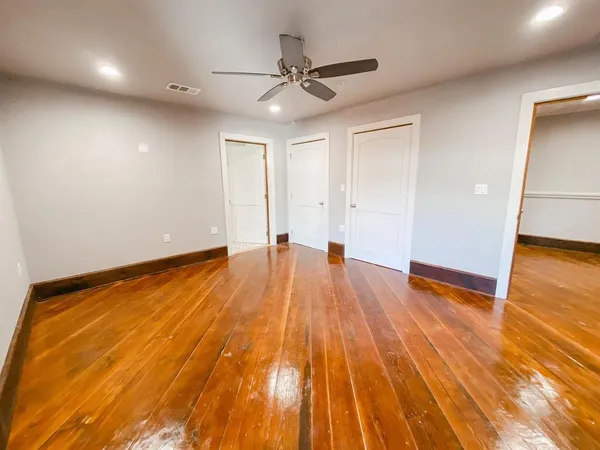 a view of room with wooden floor and a ceiling fan