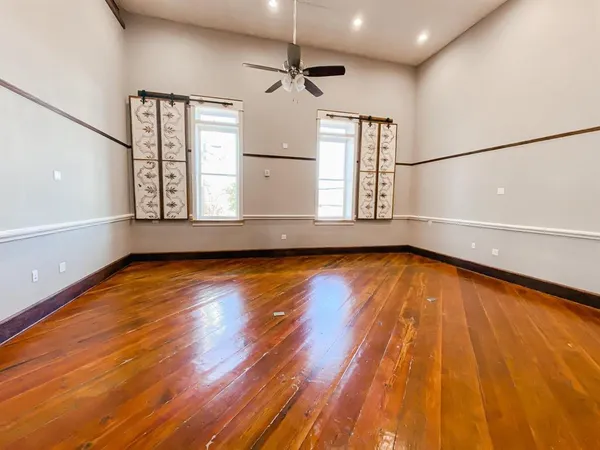 a view of empty room with wooden floor and fan