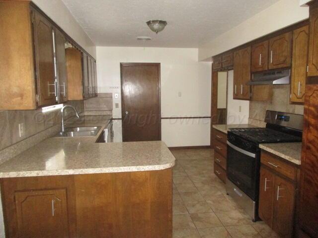 4904 South Georgia Street Amarillo, TX 79110 - Photo 9 of 12 a kitchen with stainless steel appliances granite countertop a sink stove and refrigerator