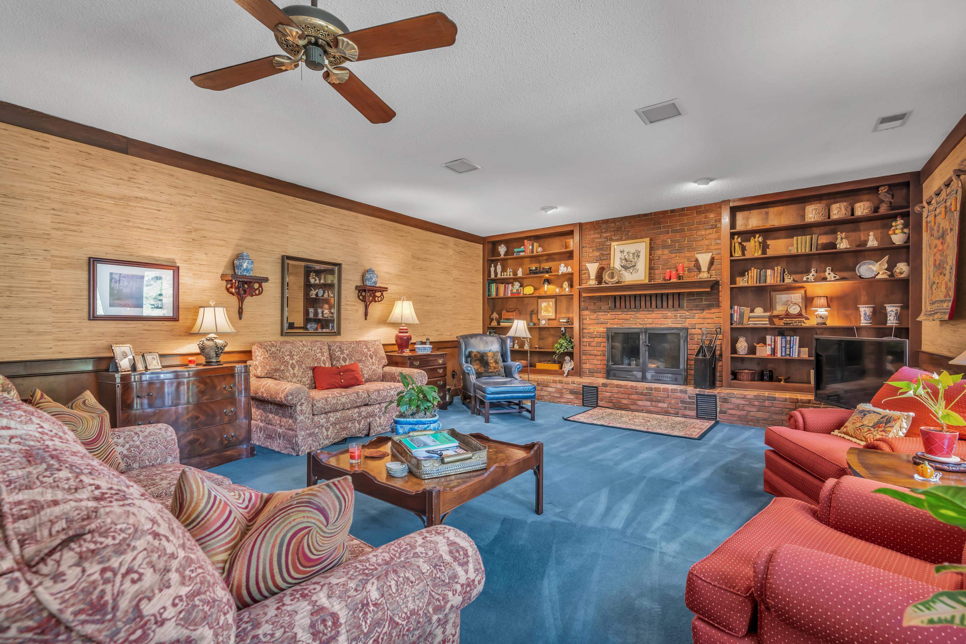 2002 Magnolia Ridge Cove Germantown, TN 38138 - Photo 10 of 40 Carpeted living room featuring a fireplace, wooden walls, built in features, and ceiling fan