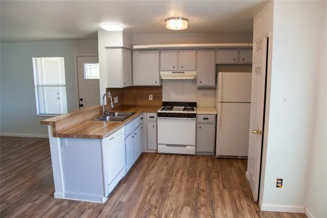 a kitchen with a refrigerator a sink and wooden floor