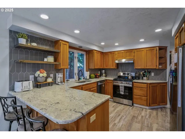 a kitchen with stainless steel appliances granite countertop a sink a stove and a refrigerator