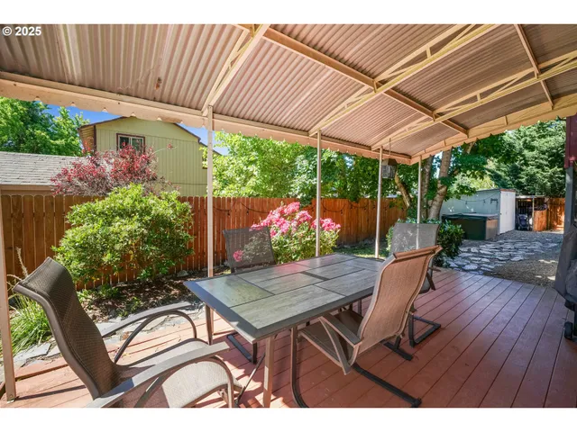 a view of a patio with table and chairs under an umbrella with a small yard