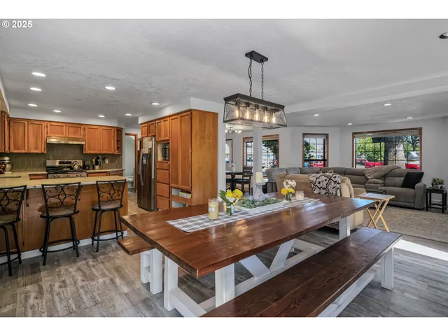 a kitchen with stainless steel appliances kitchen island granite countertop a table chairs and a refrigerator