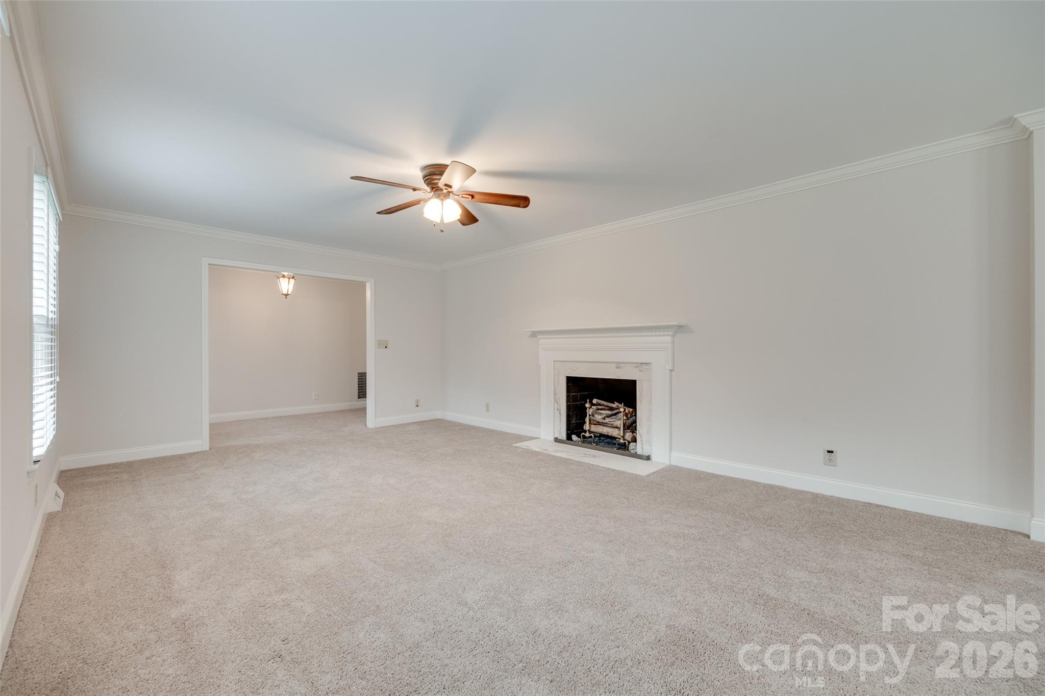 1003 Chesterfield Avenue Lancaster, SC 29720 - Photo 3 of 31 an empty room with a fireplace and a chandelier fan