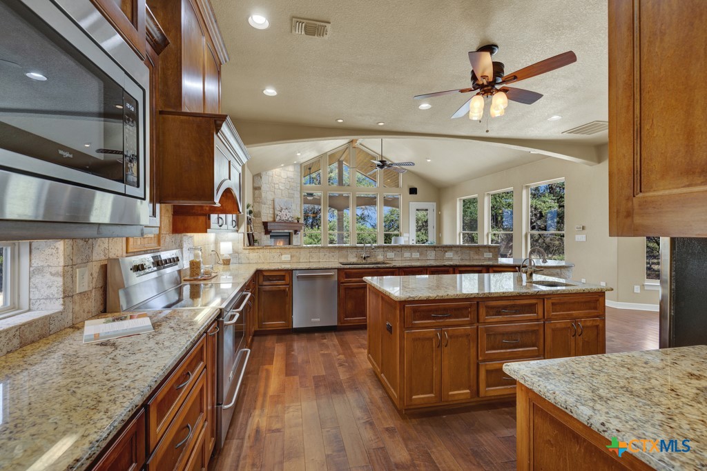 7607 Sky Loop Garden Ridge, TX 78266 - Photo 10 of 43 a kitchen with stainless steel appliances granite countertop a sink a stove and a wooden floors