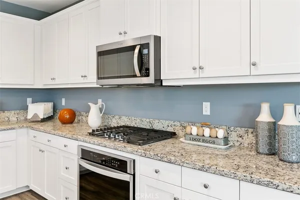 a kitchen with granite countertop white cabinets and a white stove