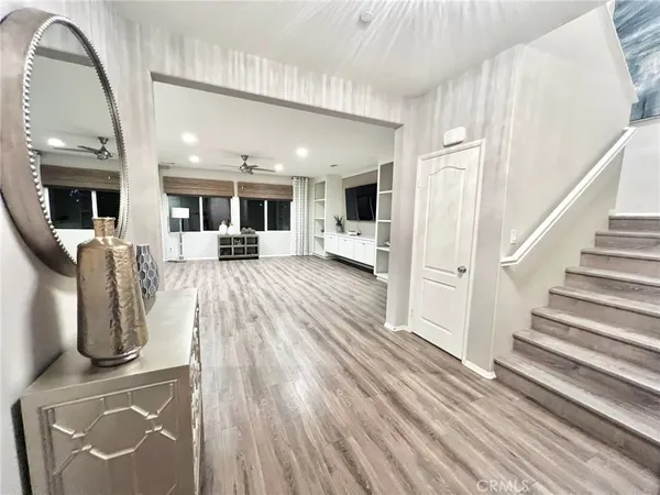 a view of a living room with wooden floor and white walls