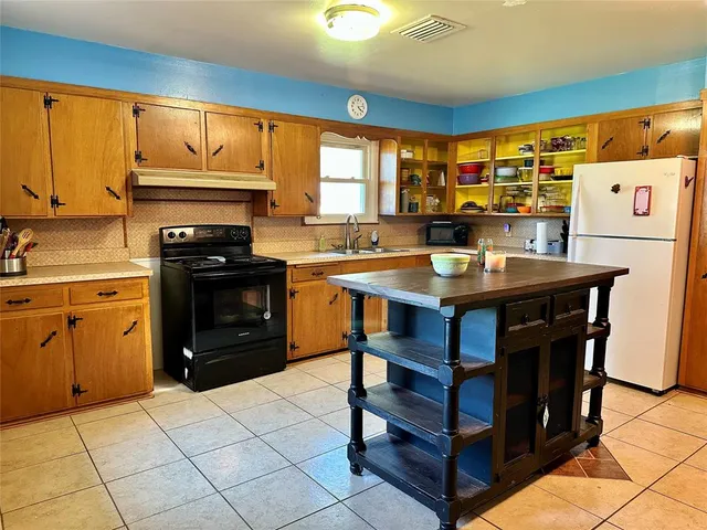 a kitchen with a stove a sink a refrigerator and wooden cabinets