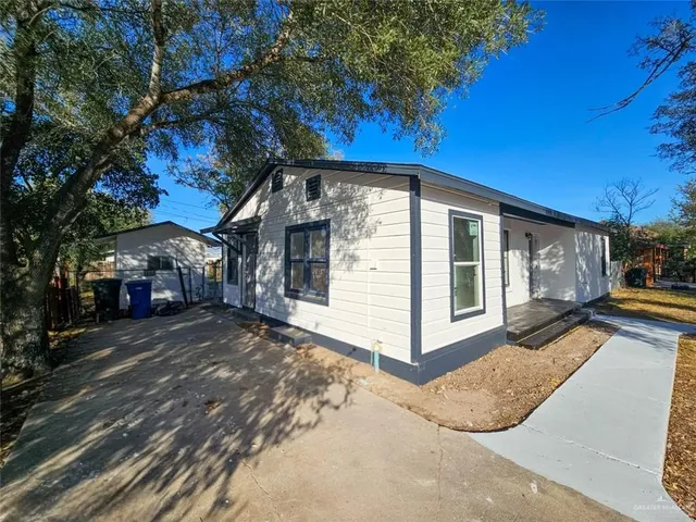 a view of a white house with a large tree