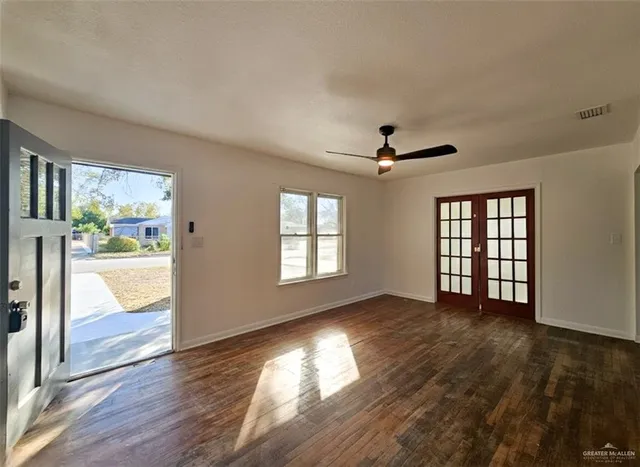 a view of an empty room with wooden floor and a window