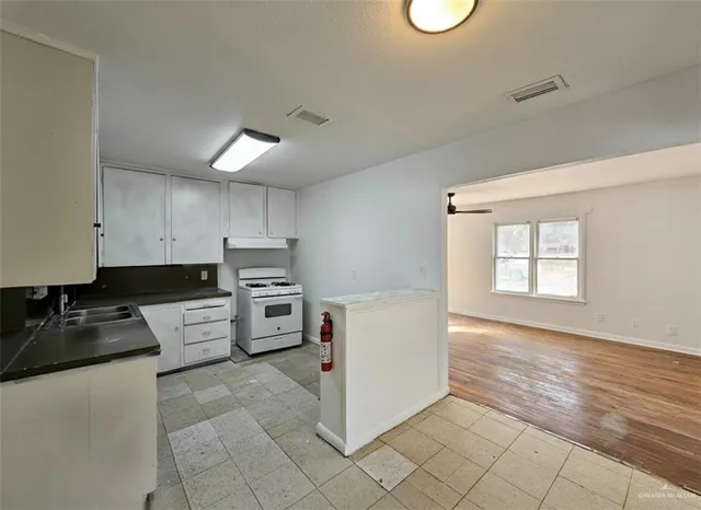 a kitchen with granite countertop a stove a sink and a refrigerator