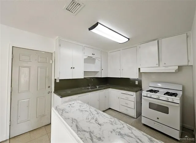 a kitchen with granite countertop a sink a stove and cabinets