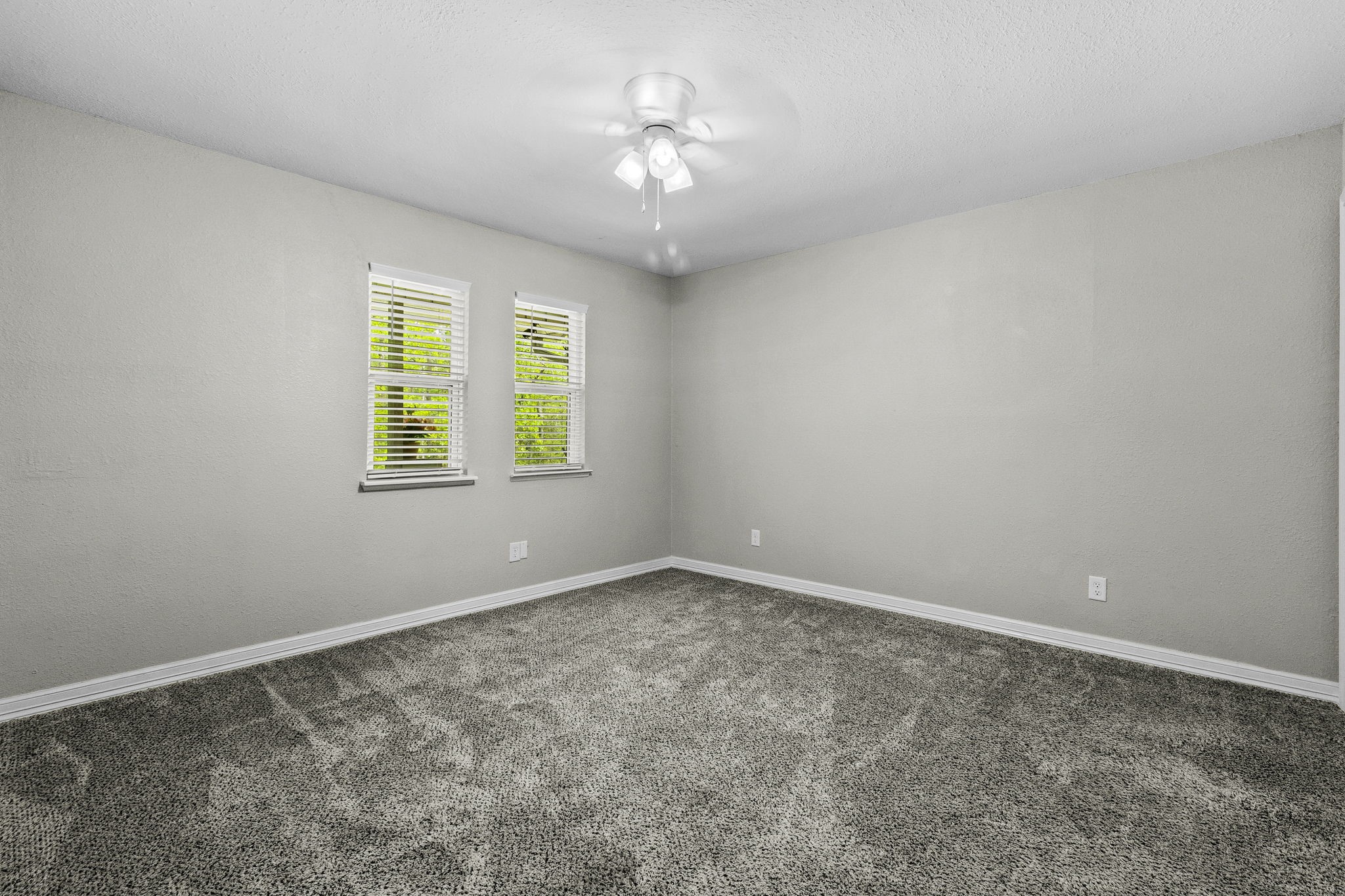 21 Red Oak Circle Point Blank, TX 77364 - Photo 14 of 32 This is a bright, neutral-toned room with two windows, gray carpet, and a ceiling fan, providing a cozy and versatile space.