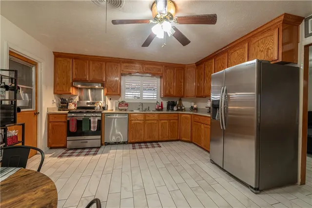 a kitchen with stainless steel appliances a refrigerator a stove a sink and a microwave