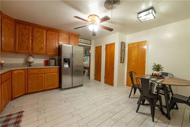 a kitchen with stainless steel appliances a table chairs refrigerator and cabinets