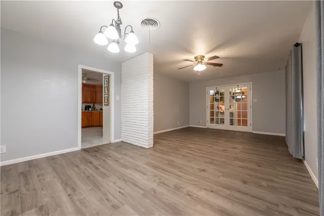 a view of an empty room with a window and wooden floor