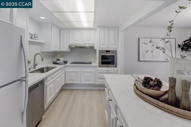 a kitchen with stainless steel appliances a sink a stove a refrigerator and cabinets