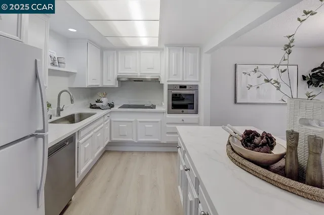 a kitchen with stainless steel appliances a sink a stove a refrigerator and cabinets