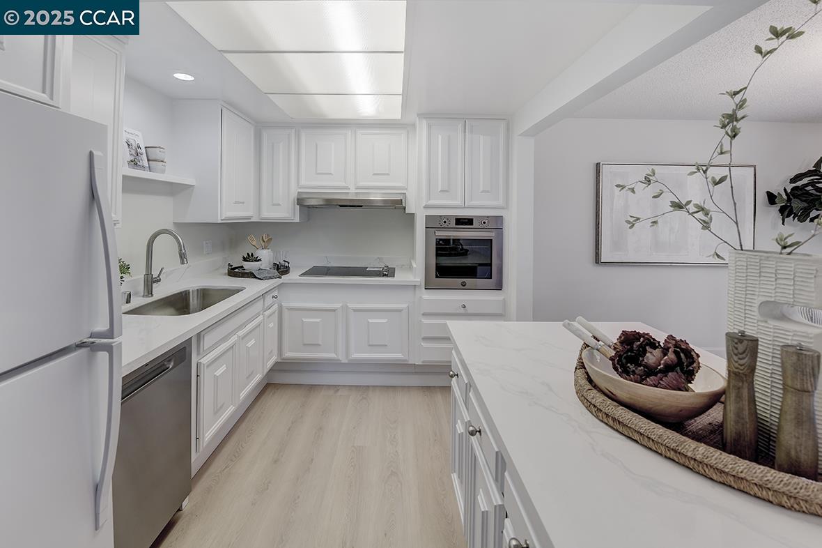 2940 Tice Creek Drive, Unit 6 Walnut Creek, CA 94595 - Photo 9 of 49 a kitchen with stainless steel appliances a sink a stove a refrigerator and cabinets
