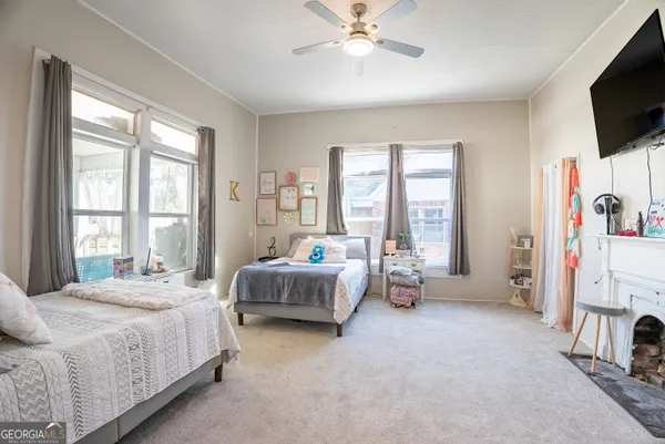 a bedroom with bed and a flat tv screen next to a window
