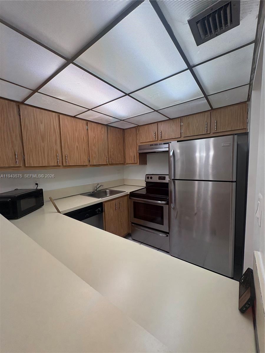 5981 Washington Street, Unit 215 Hollywood, FL 33023 - Photo 13 of 24 a kitchen with granite countertop a refrigerator and a stove top oven