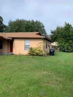 a view of a white house with a big yard and large trees