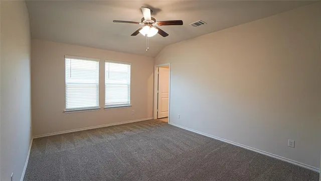 an empty room with chandelier fan and windows