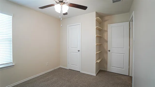 a view of empty room with window and ceiling fan