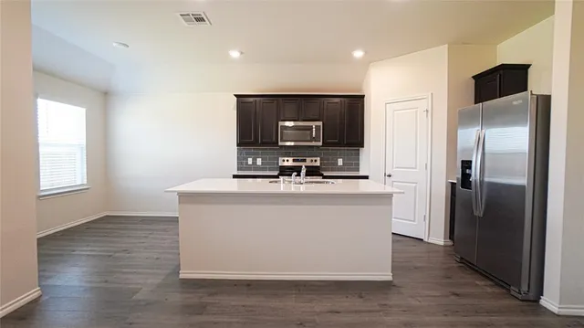 a view of kitchen with stainless steel appliances granite countertop a stove top oven and a refrigerator