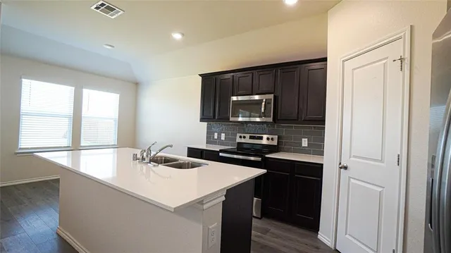 a kitchen with a sink a stove top oven and wooden floor