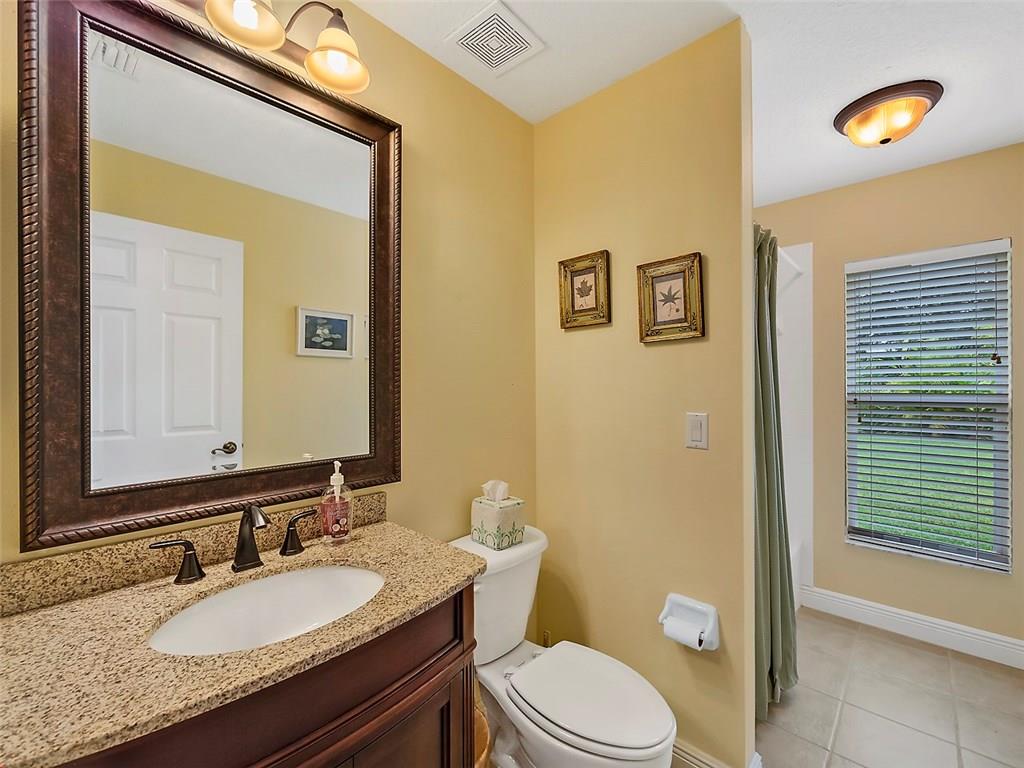 1945 Southwest Panther Trace Stuart, FL 34997 - Photo 14 of 18 a bathroom with a granite countertop toilet a sink and a mirror