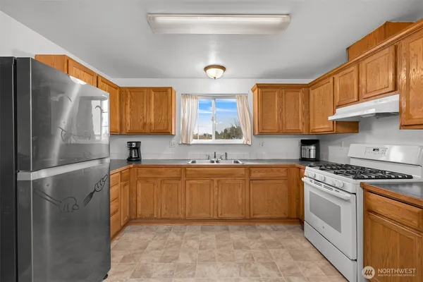 a kitchen with stainless steel appliances granite countertop a sink stove refrigerator granite counter tops and a window
