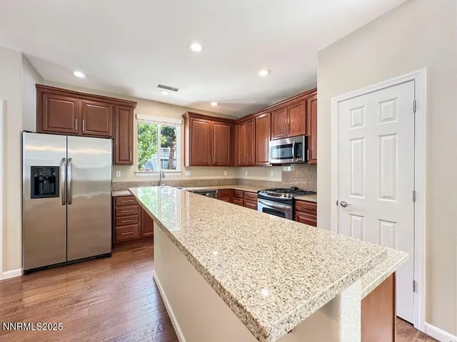 a kitchen with stainless steel appliances granite countertop a refrigerator a sink a stove a microwave and island